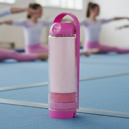 Pink koor refillable bottle with a handle on a blue mat, with people in the background.
